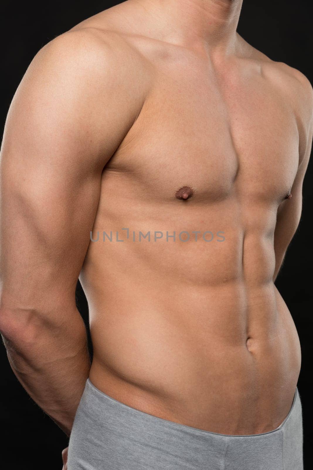 Young shirtless man against black studio background