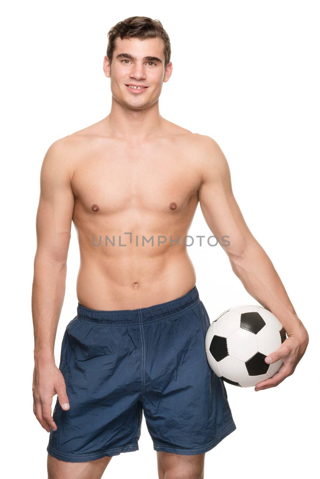Young man with a soccer ball in front of white studio background