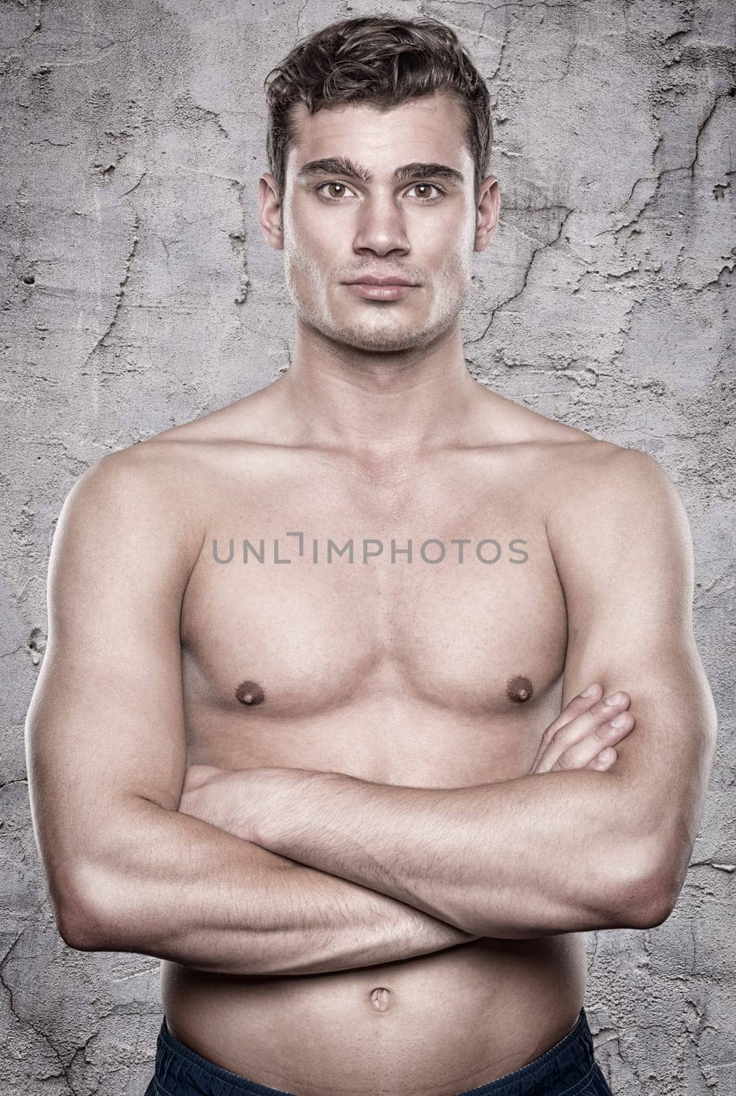 Young shirtless man in front of a stone wall