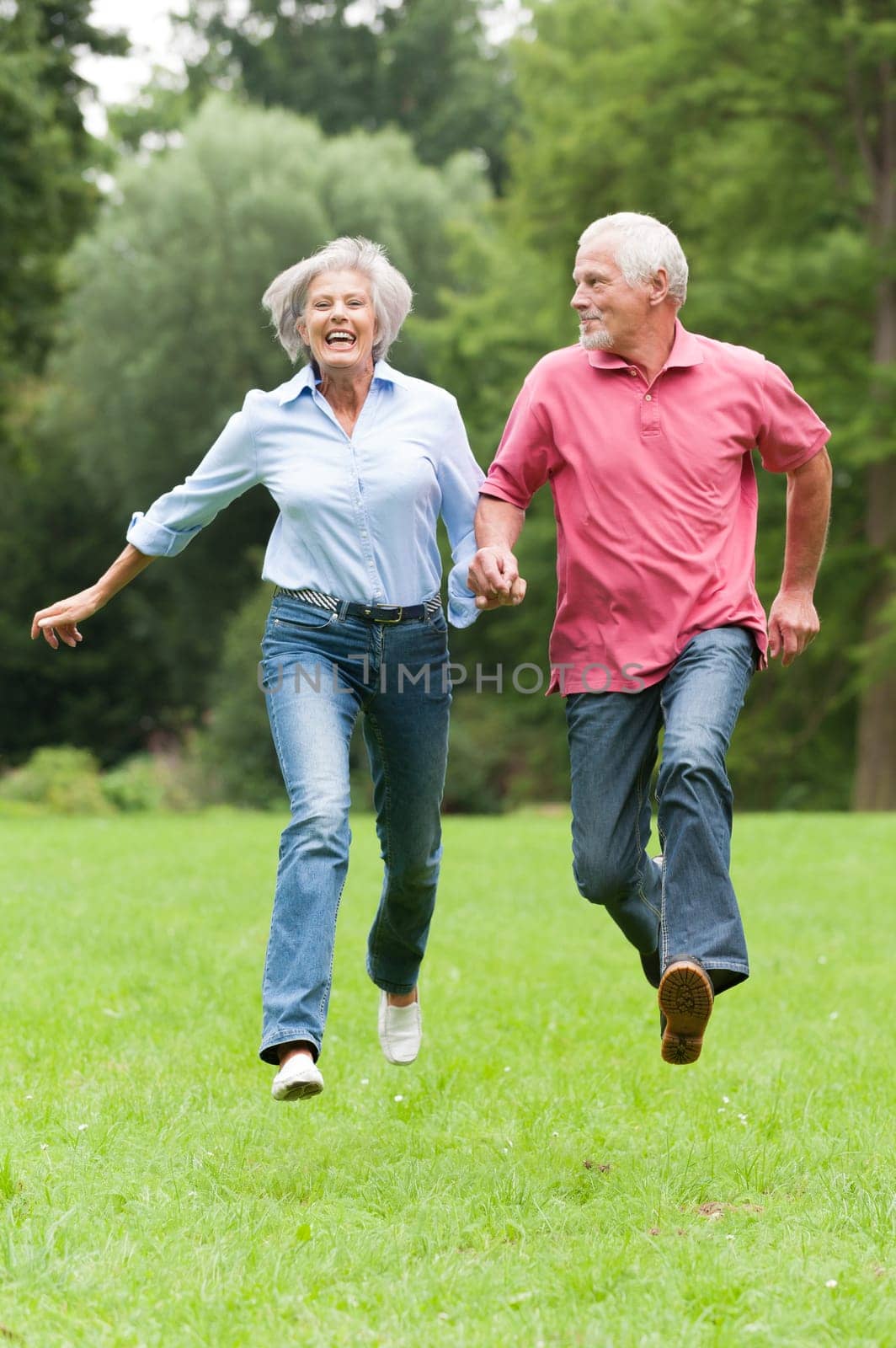 Active retired couple jumping in a park