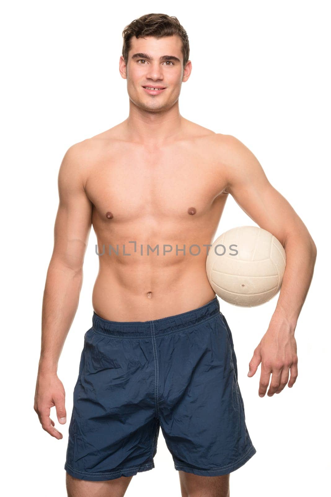 Young man with a volleyball in front of white studio background
