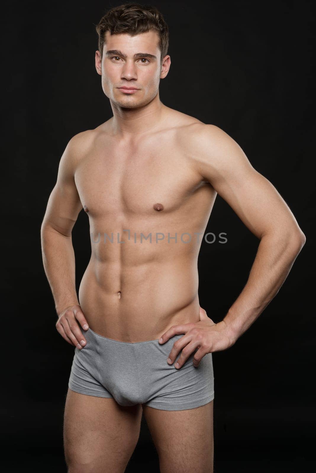 Young shirtless man against black studio background