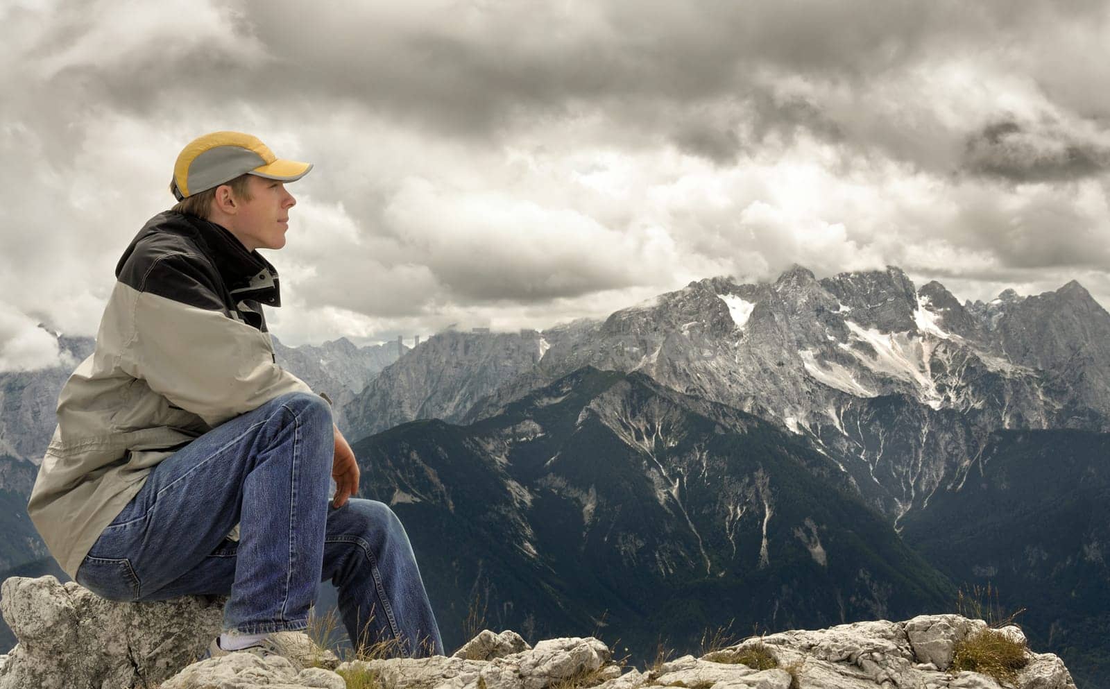 Young man sitting at the summit and enjoying the view of the mountain landscape