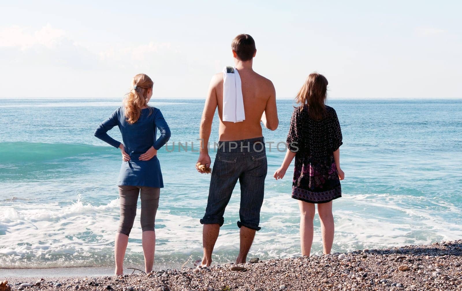 man and two girls looking at the sea