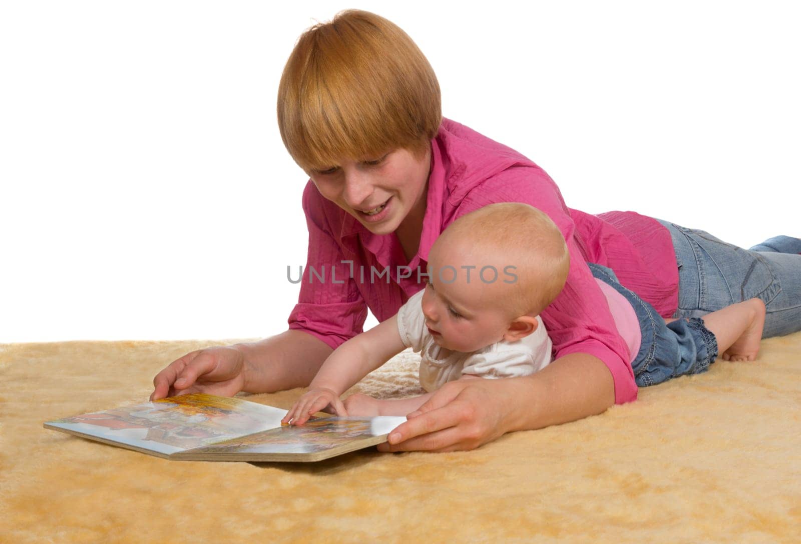 Mother lying on the floor with her arm protectively around her cute young baby looking at a book together