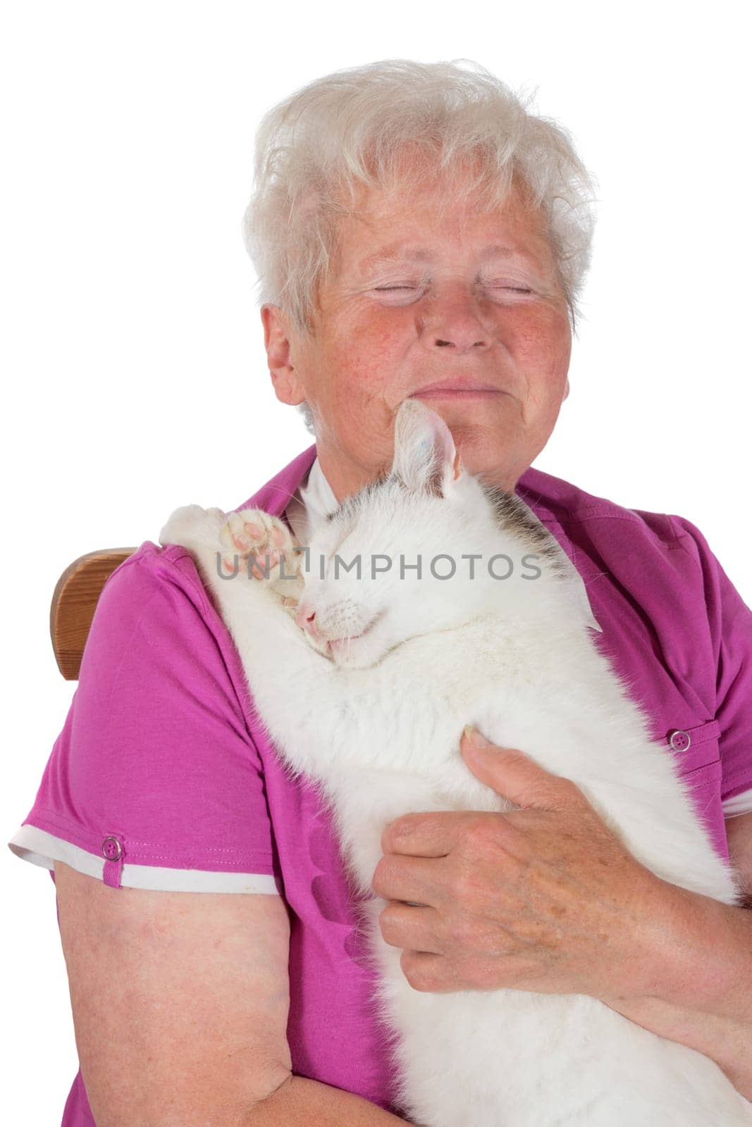 Pensioner hugging her white tomcat to her chest and savouring the moment as she sits with her eyes closed as the cat curls his paws in affection