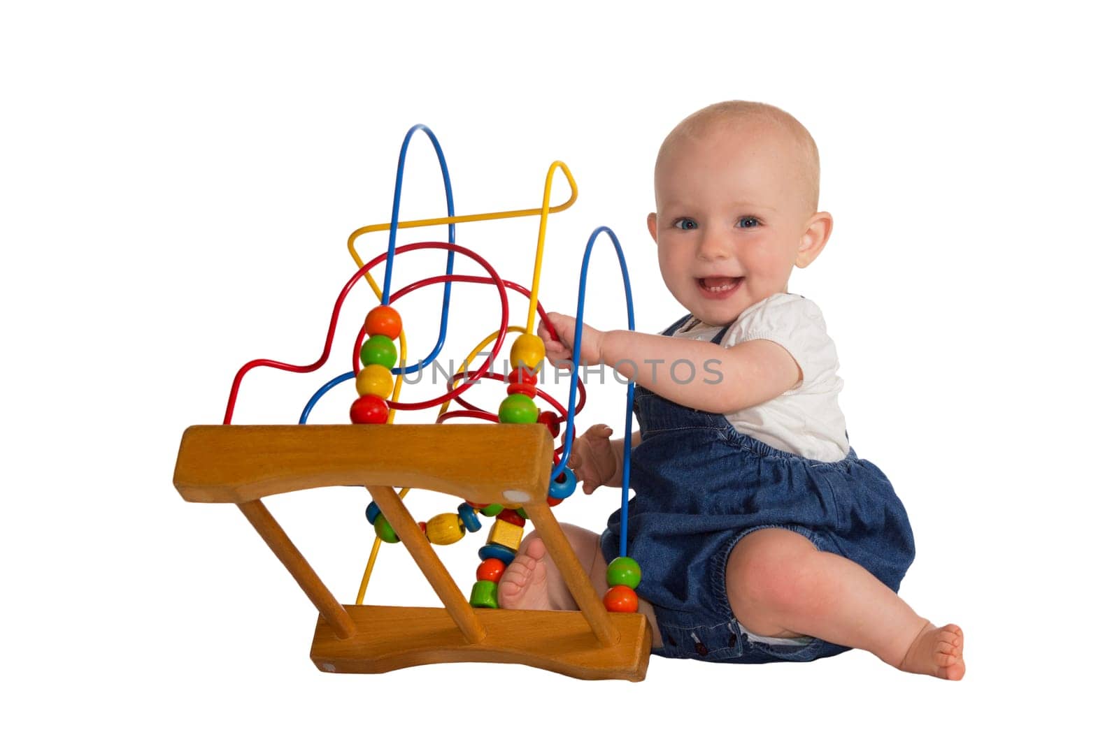Happy cute baby playing on the floor with a wooden educational toy with looped wires for teaching coordination and colours isolated on white