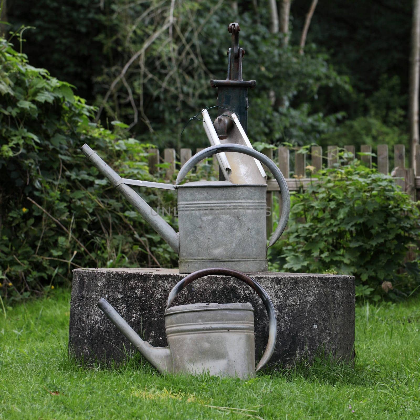 Old fountain with watering cans in the garden
