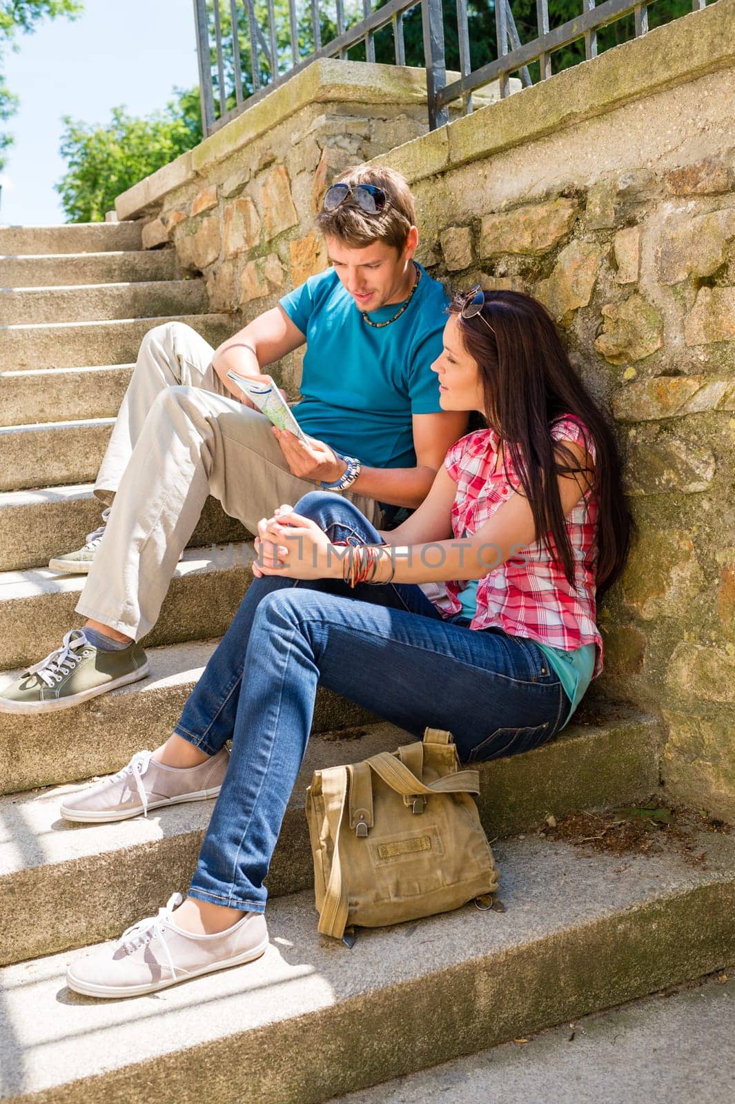 Young couple looking at city map sunny day sightseeing together