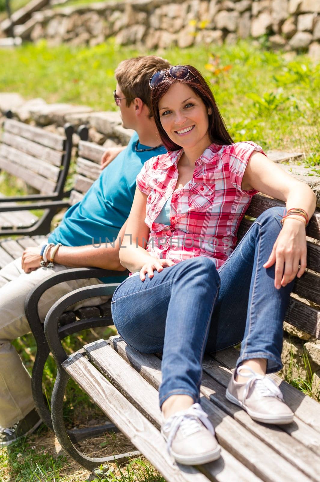 Young couple sitting on bench in park resting happy smiling