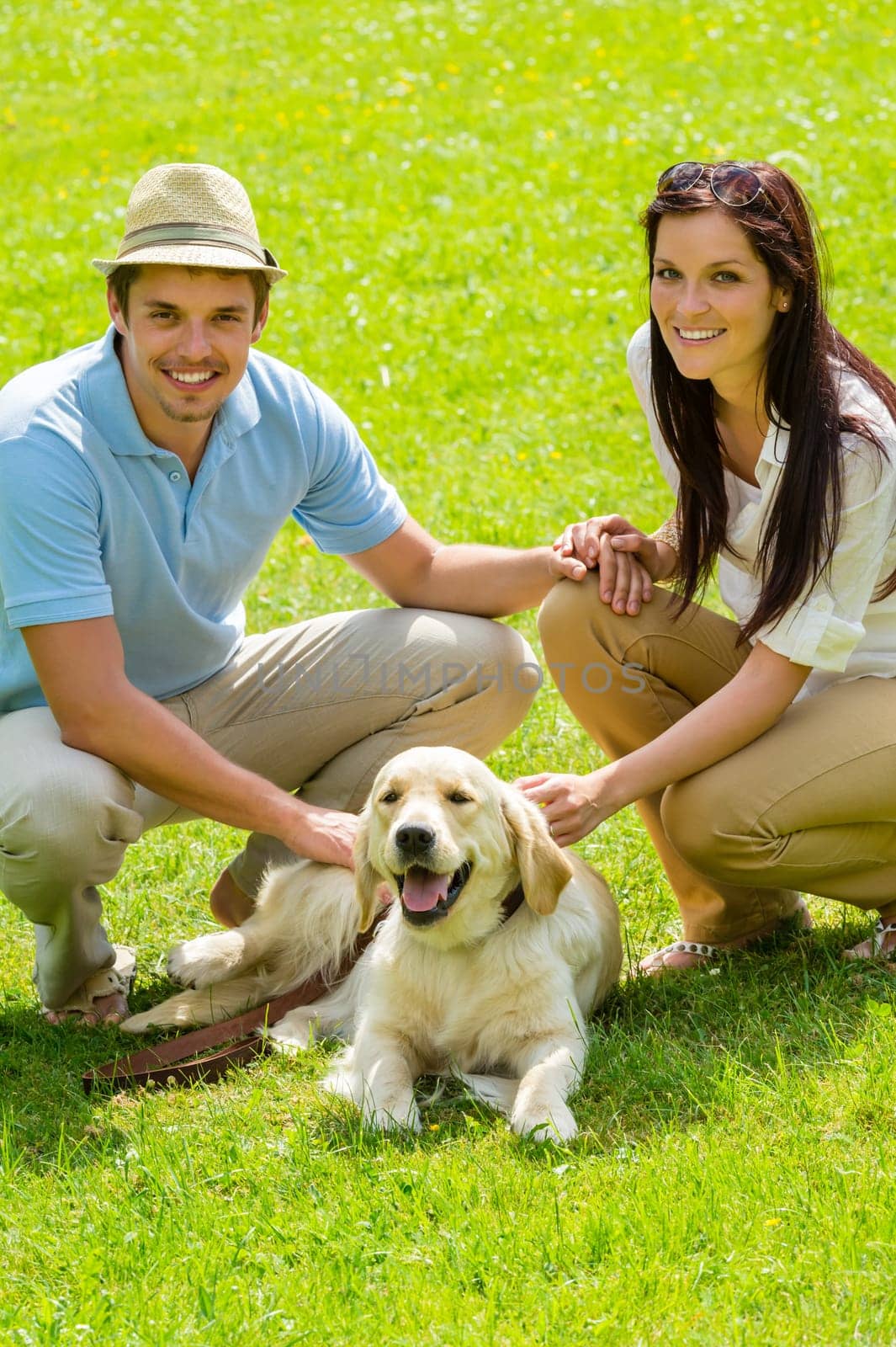 Young happy couple with Labrador dog smiling in park