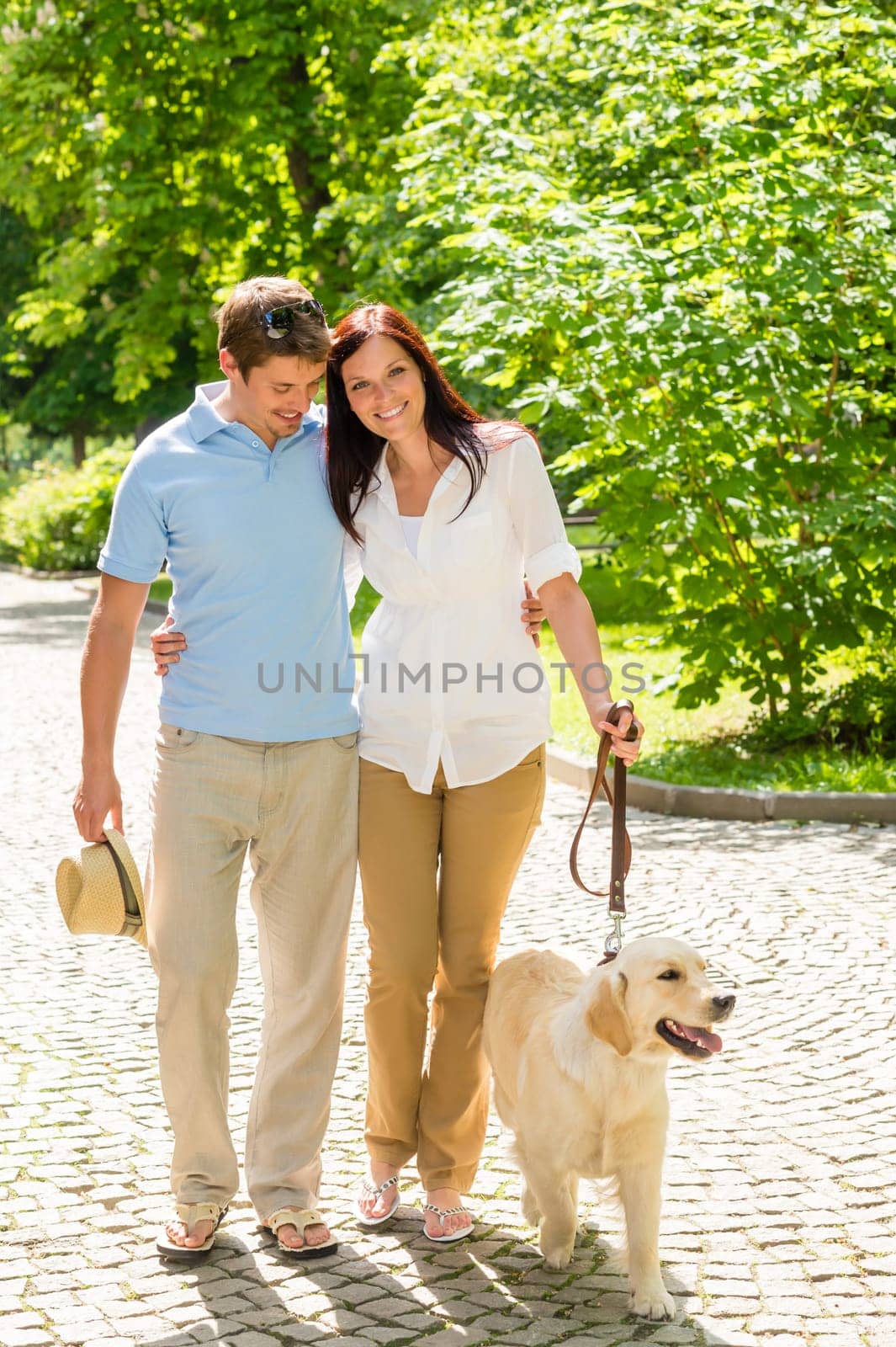 Couple in love walking Labrador dog in park sunny day
