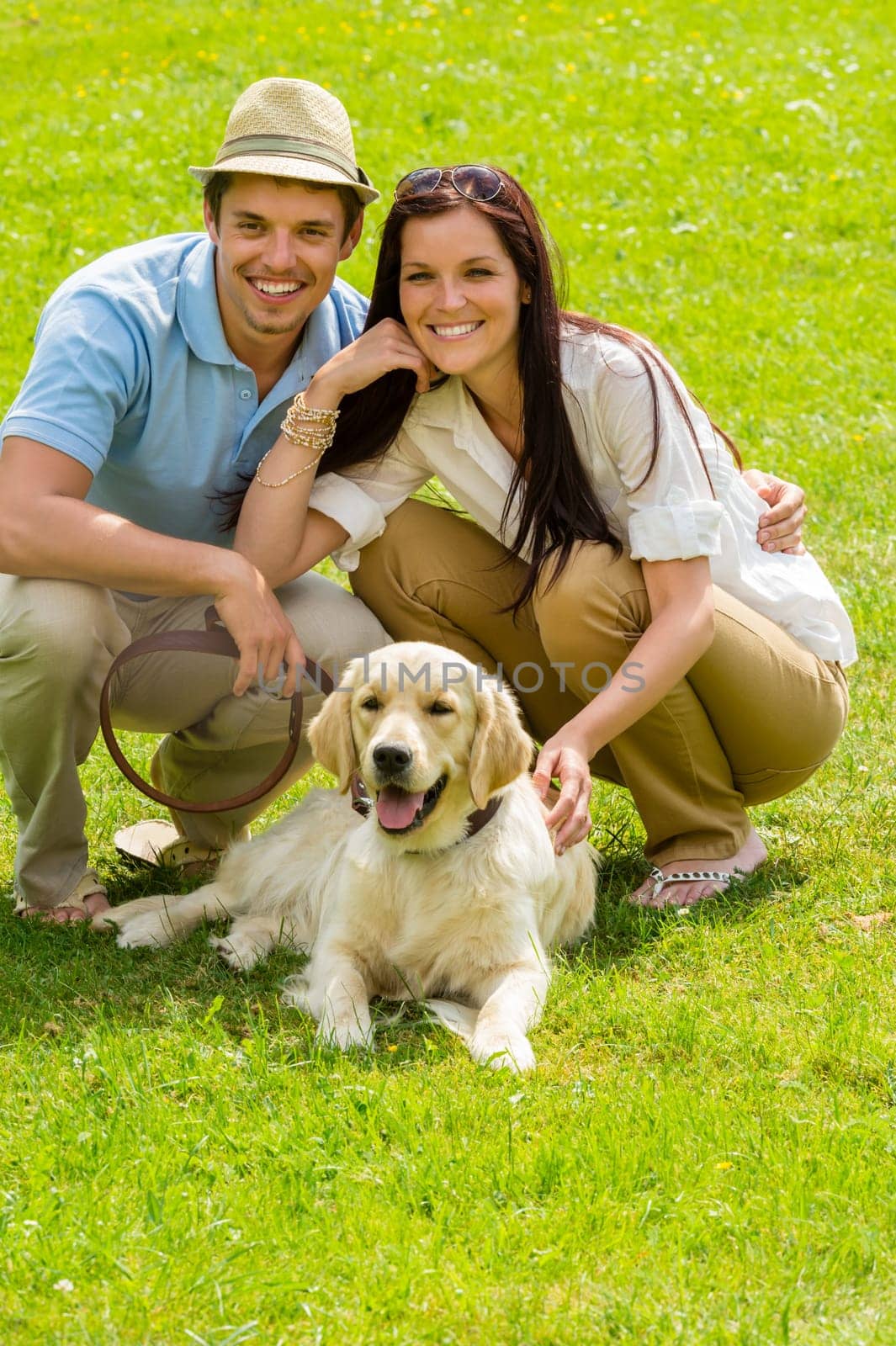 Young happy couple with Labrador dog sitting on grass