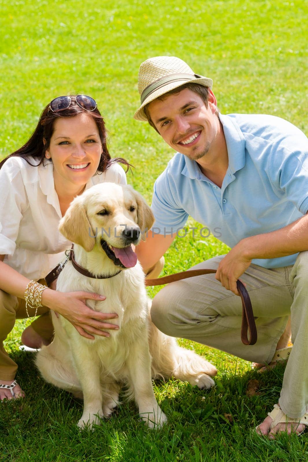 Young happy couple with Labrador dog smiling in park