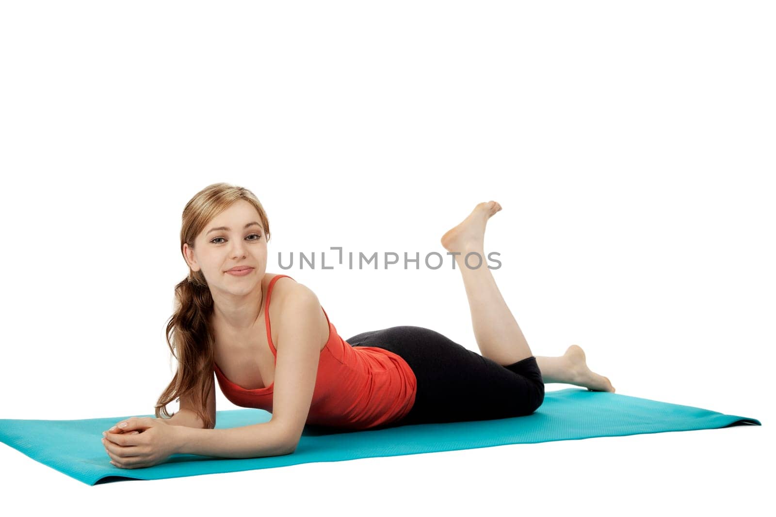 Pretty young sportswoman lying on a fitness mat on white background