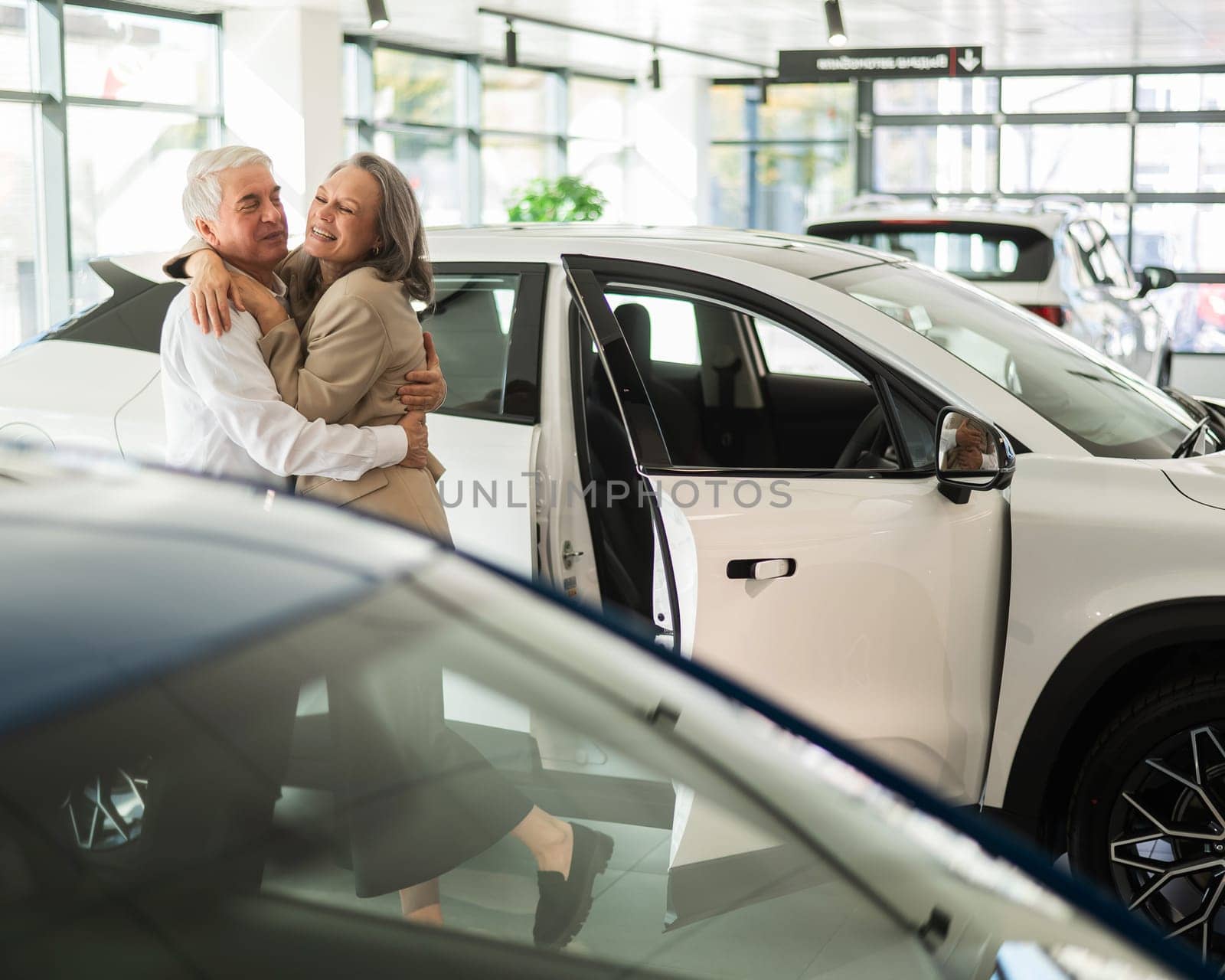 Mature Caucasian couple hugging. Elderly man and woman buying a new car