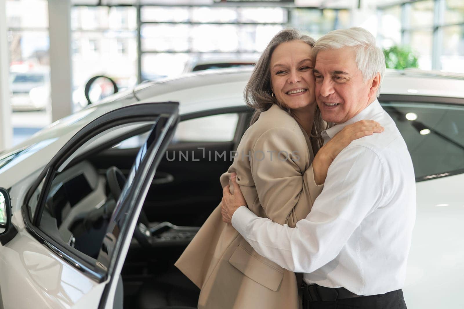 Mature Caucasian couple hugging. Elderly man and woman buying a new car. by mrwed54