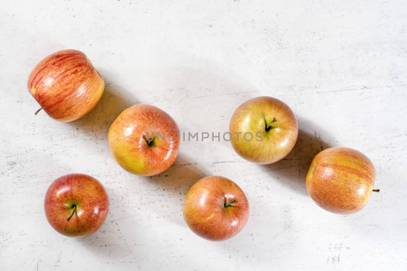 Tabletop view, six shiny apples (kiku variety) on white working board