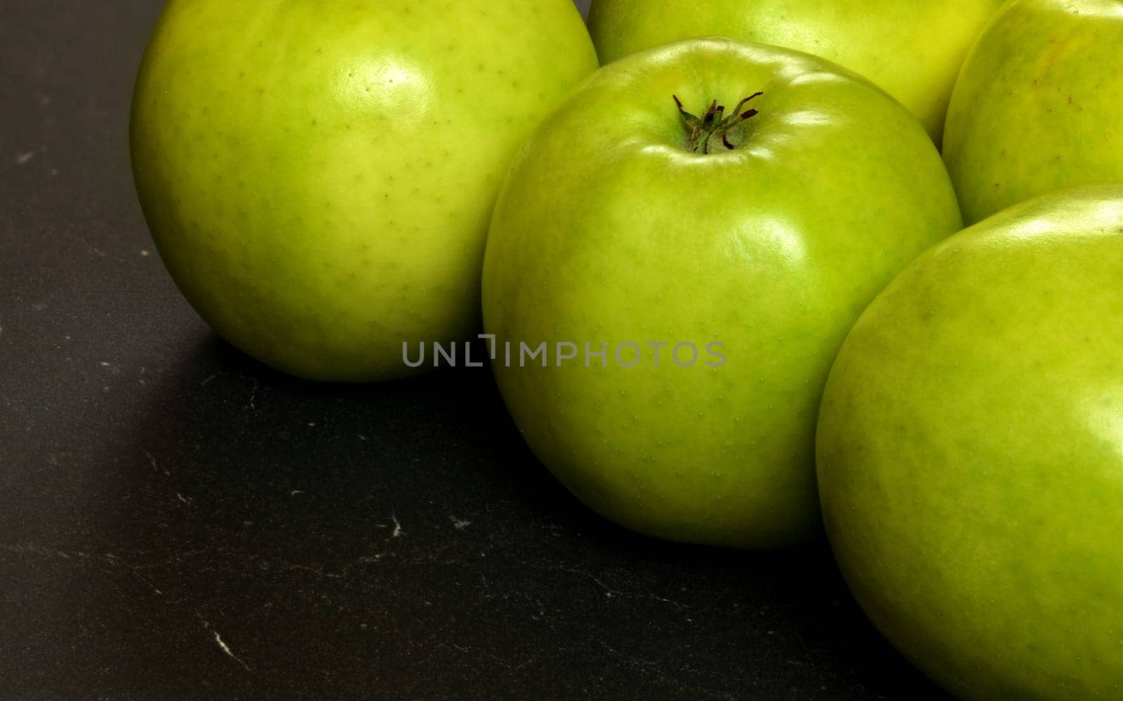 Closeup of green apples on black board