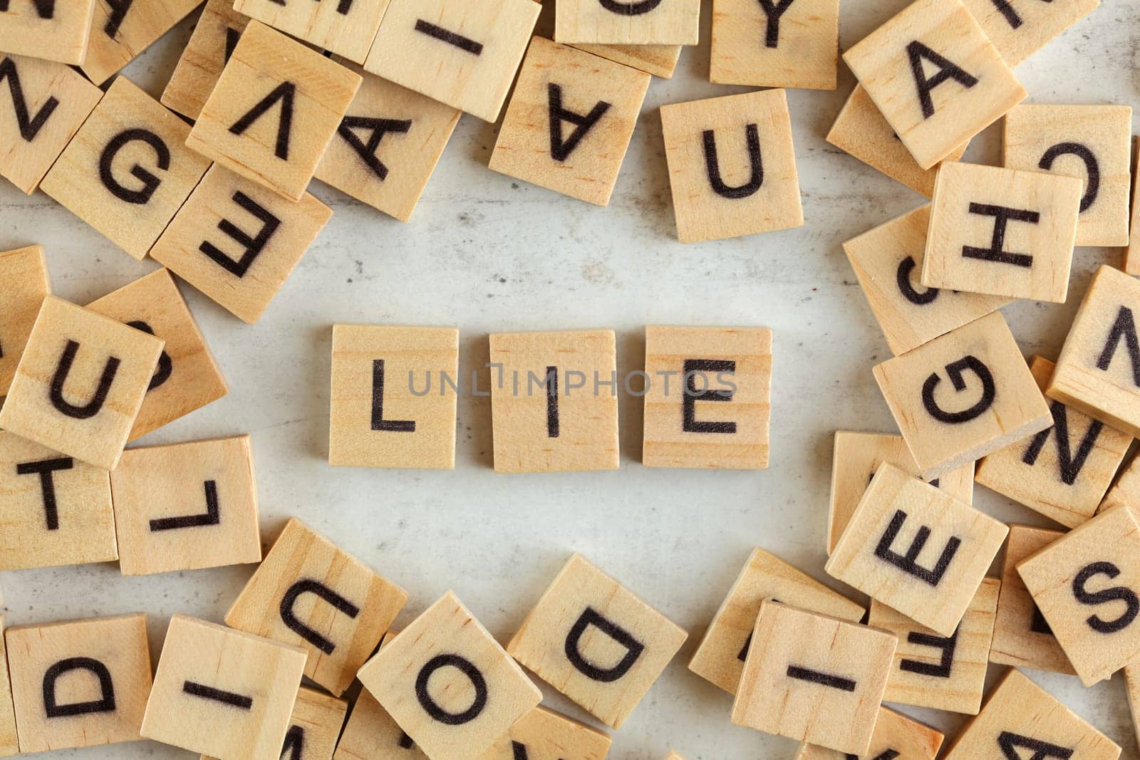 Top down view, pile of square wooden blocks with word LIE on white board. 