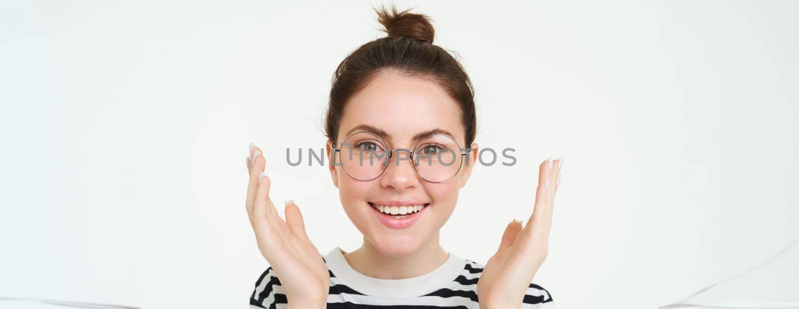 Close up portrait of happy, beautiful young woman clapping, looks pleased and smiling, applause you, standing over white background.