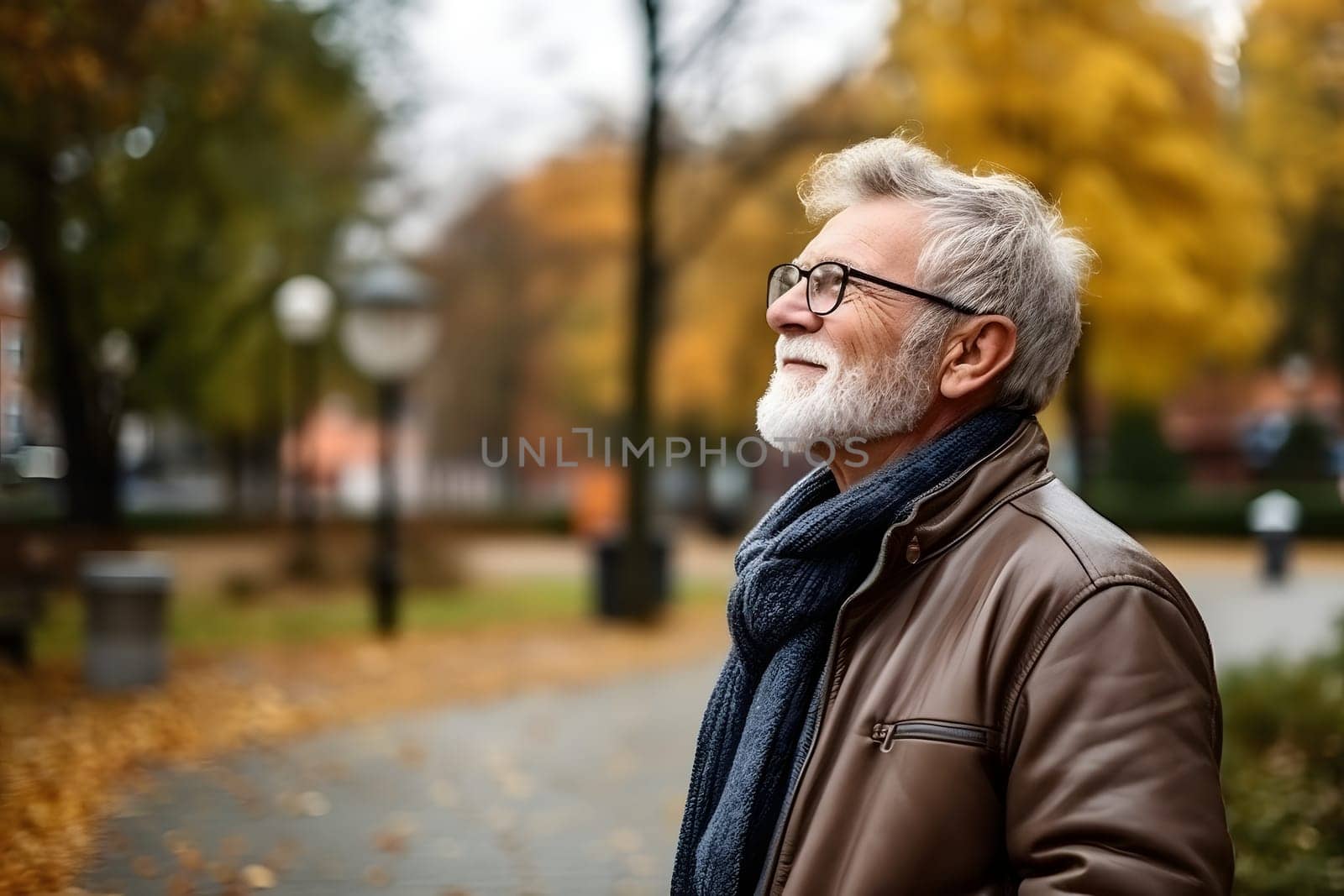 positive mature man in glasses with a cheerful mood, walking in the park. He has energy, a bright smile and an optimistic mood.