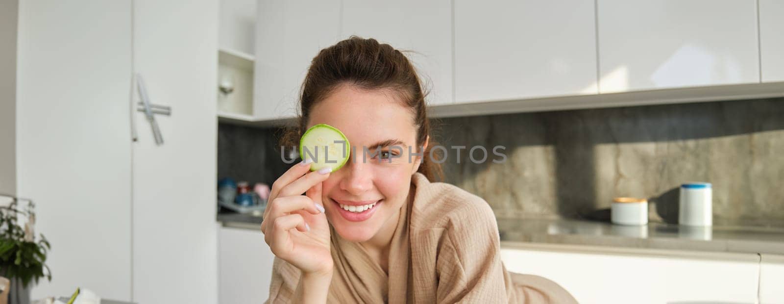 Close up portrait of happy, beautiful girl, chopping zucchini, smiling, posing in the kitchen while making food, preparing salad for lunch, eating healthy by Benzoix