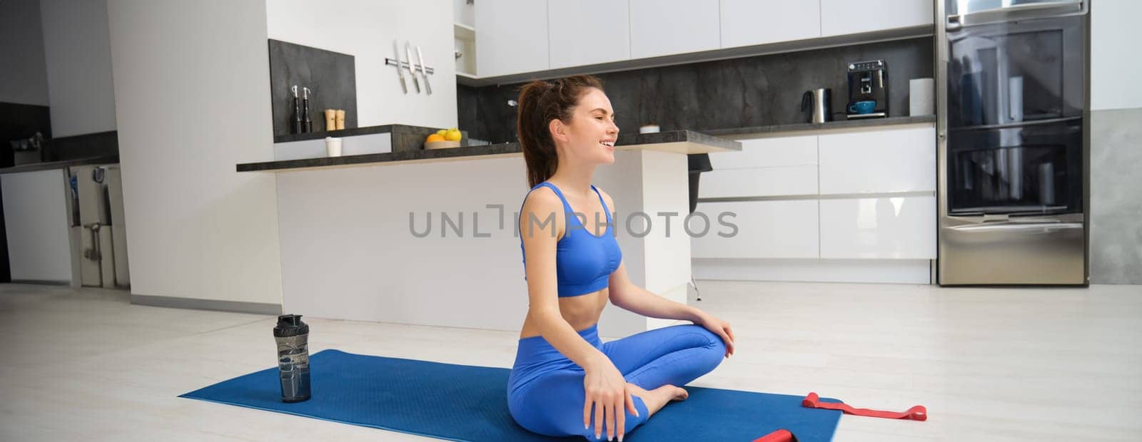 Portrait of woman concentrating on yoga breathing practice, does exercises, sits on rubber mat and meditating, workout at home.