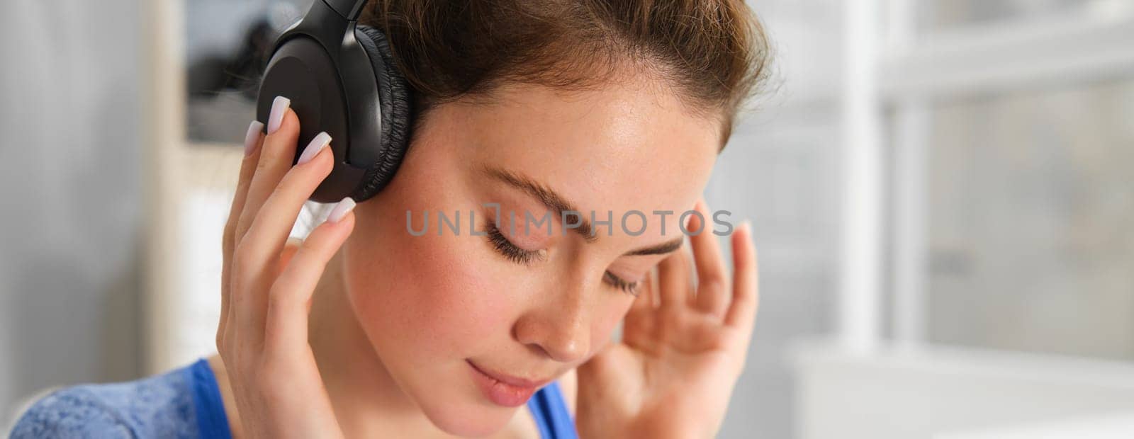 Face of beautiful woman in wireless headphones, enjoys sound, listens to music in wireless headphones.