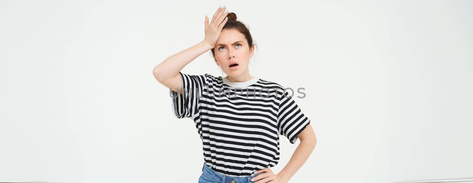 Portrait of shocked woman facepalm, slaps her forehead and looks upset, stands over white background by Benzoix