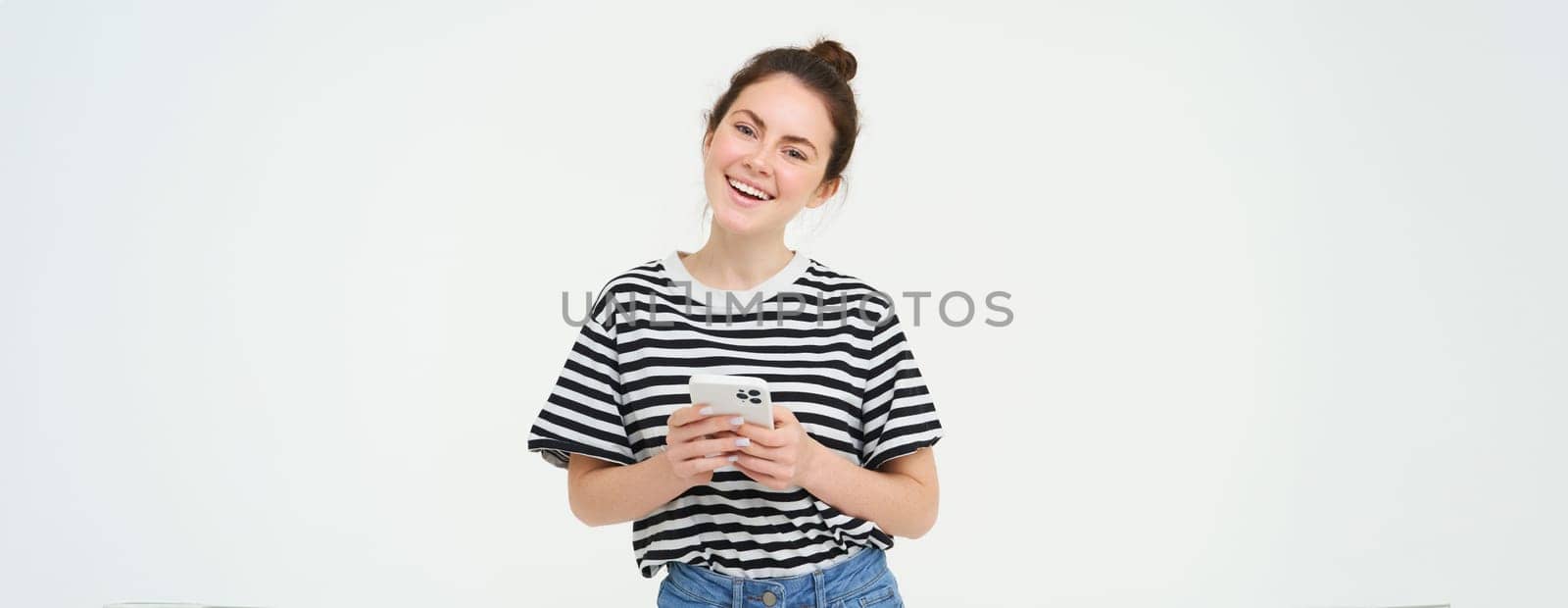 Image of young smiling woman, holding mobile phone, using smartphone application, isolated over white background by Benzoix