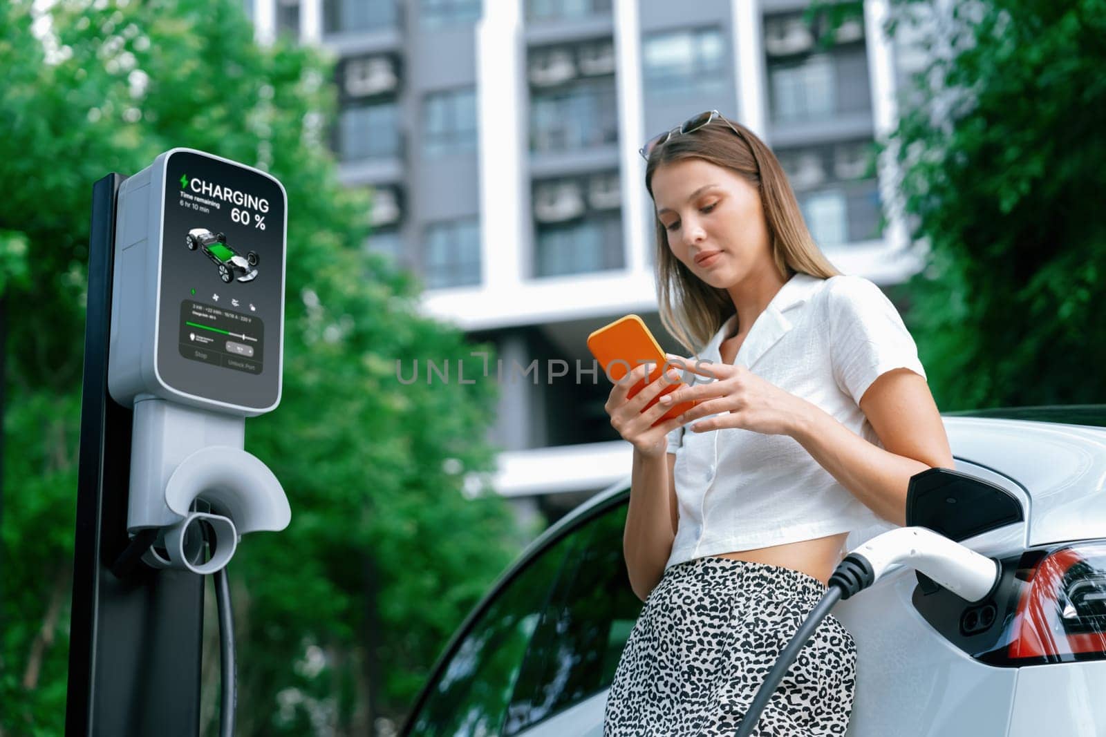 Young woman travel with EV electric car charging in green sustainable city outdoor garden in summer. Urban sustainability lifestyle by green clean rechargeable energy of electric BEV vehicle innards