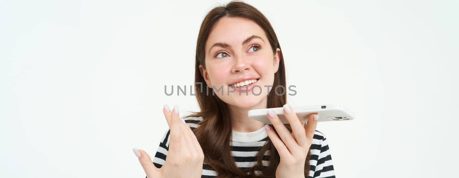 Portrait of happy young woman, student recording voice message, holding smartphone near lips, talking into mobile phone speakerphone, explaining something, singing, translating her words.