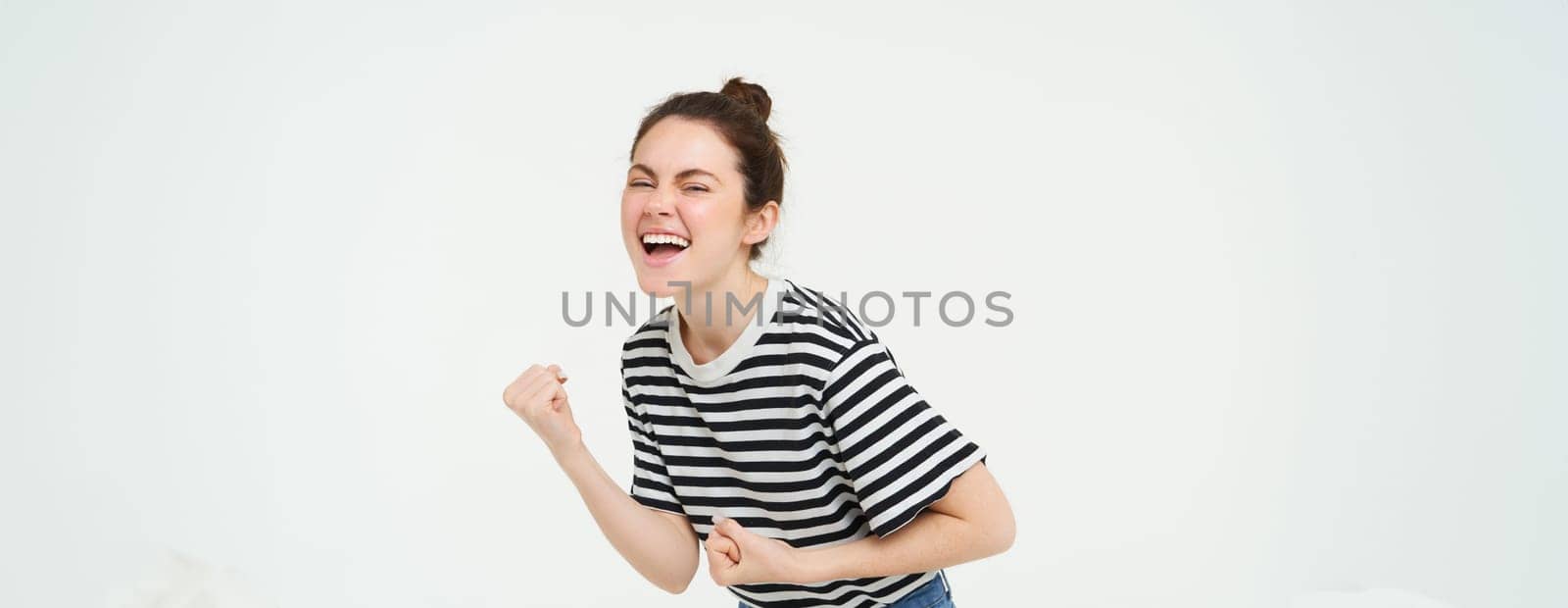 Portrait of happy woman winning, celebrating victory, rooting for team, triumphing, standing over white background.