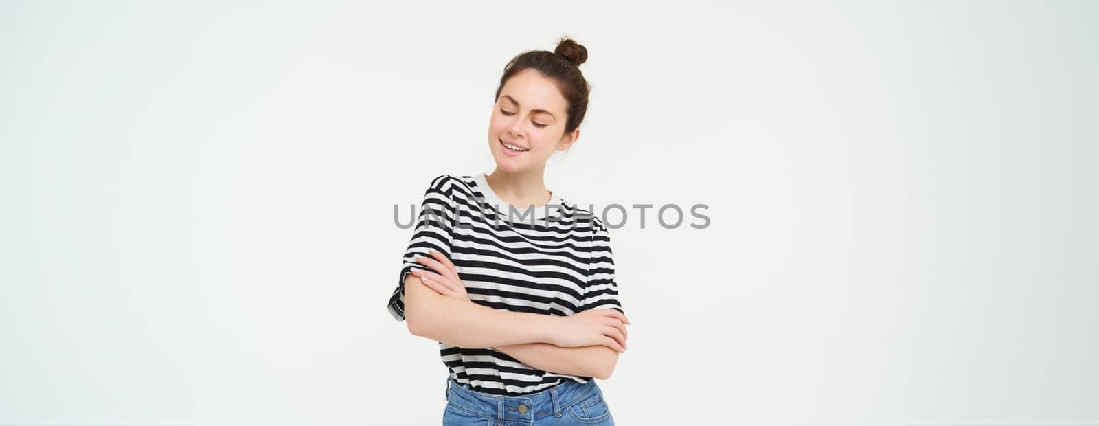 Portrait of attractive, stylish young woman, 25 years old, wearing t-shirt, cross arms against chest and smiling, looking confident, isolated over white background.