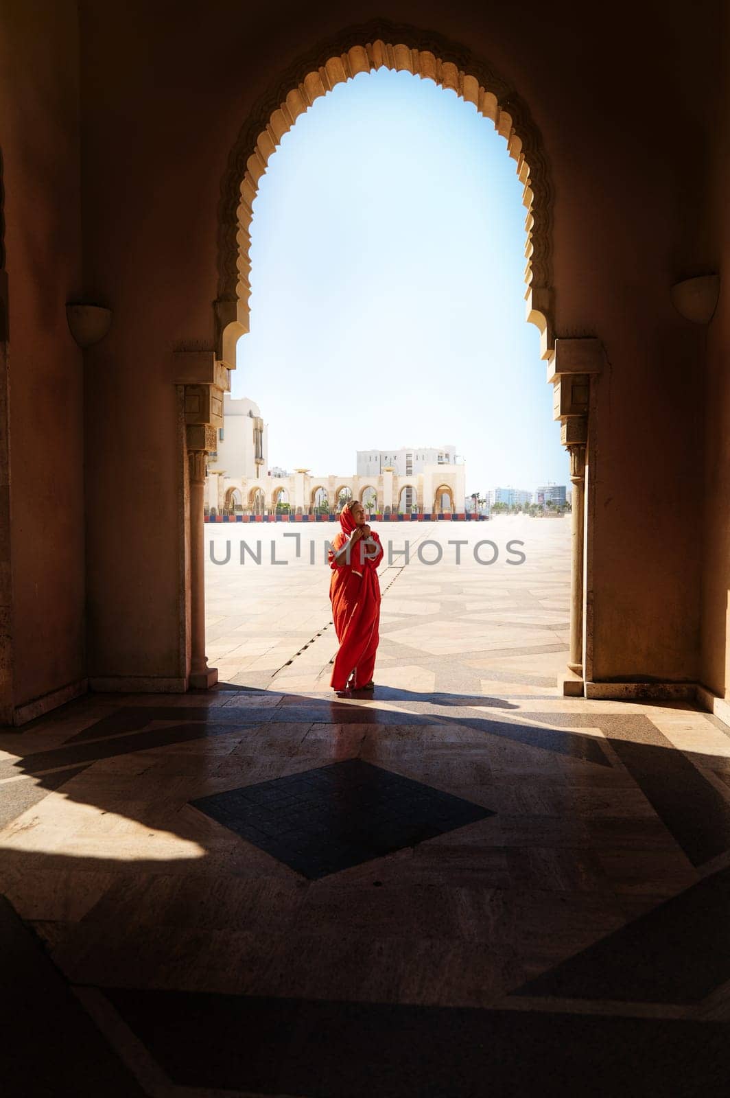 Silhouette of Muslim Arab woman in hijab and traditional clothes standing under marble arch of mosque. Islam. People and religion. Travel and tourism. Visiting Hassan II mosque in Casablanca, Morocco