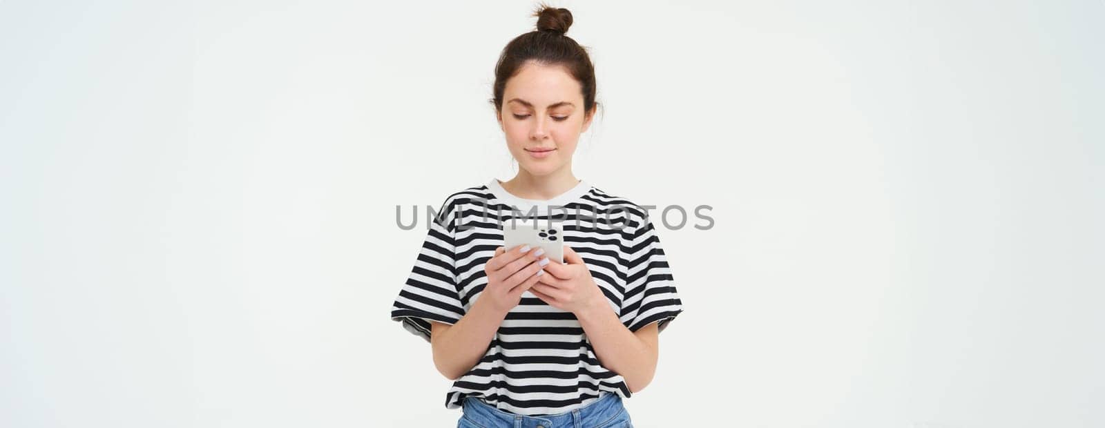Technology and lifestyle. Young woman standing over white background with smartphone.