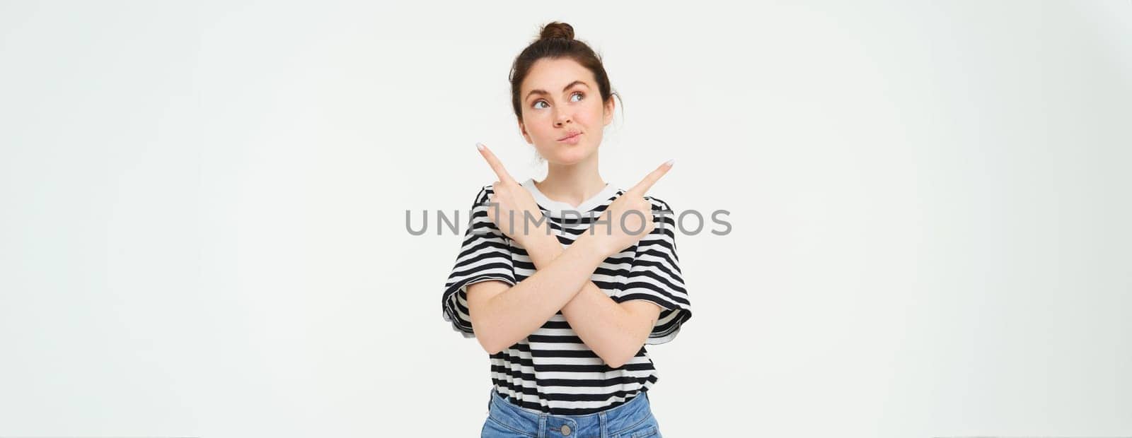 Portrait of confused woman pointing sideways, making choice, trying to choose from different options, standing thoughtful over white background.