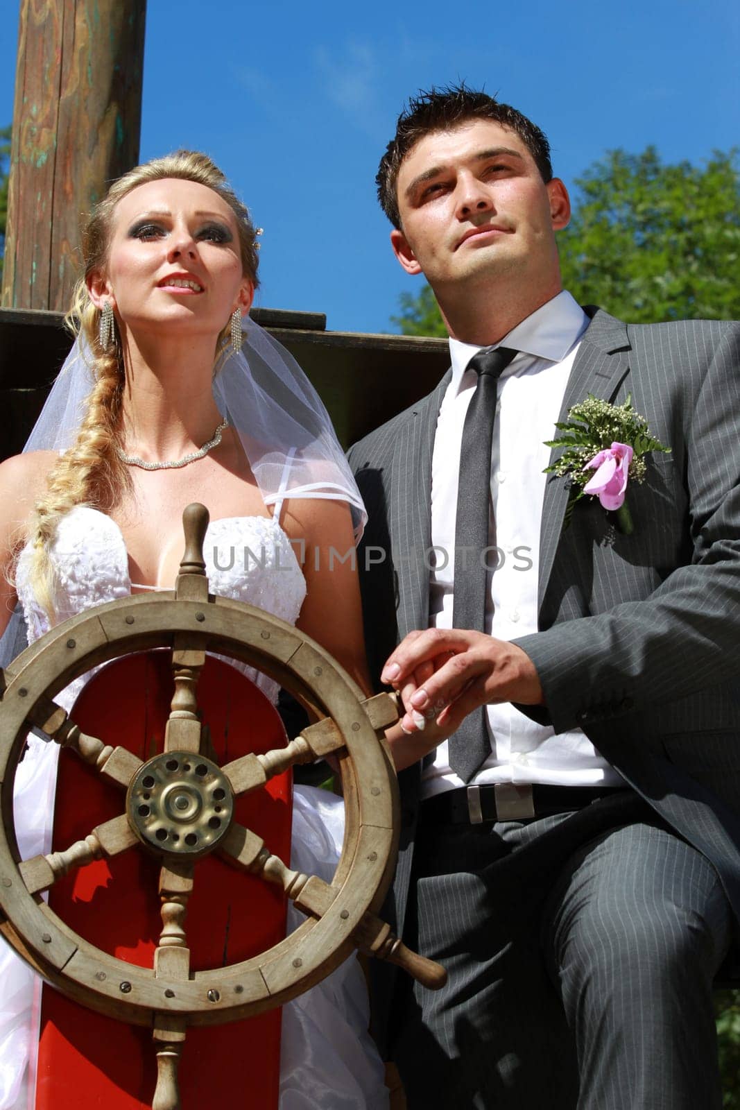 wedding couple on the antique ship with wooden steering wheel