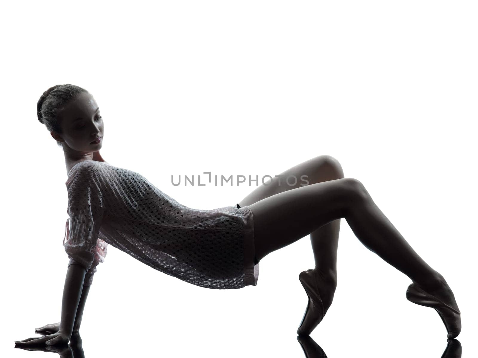 one caucasian young woman ballerina ballet dancer stretching warming up in silhouette studio on white background