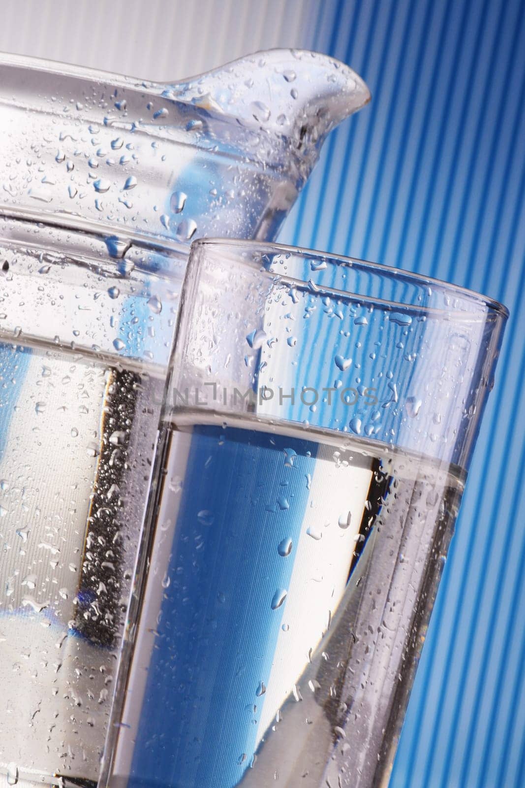 Composition with two glass of mineral water and jug on blue background