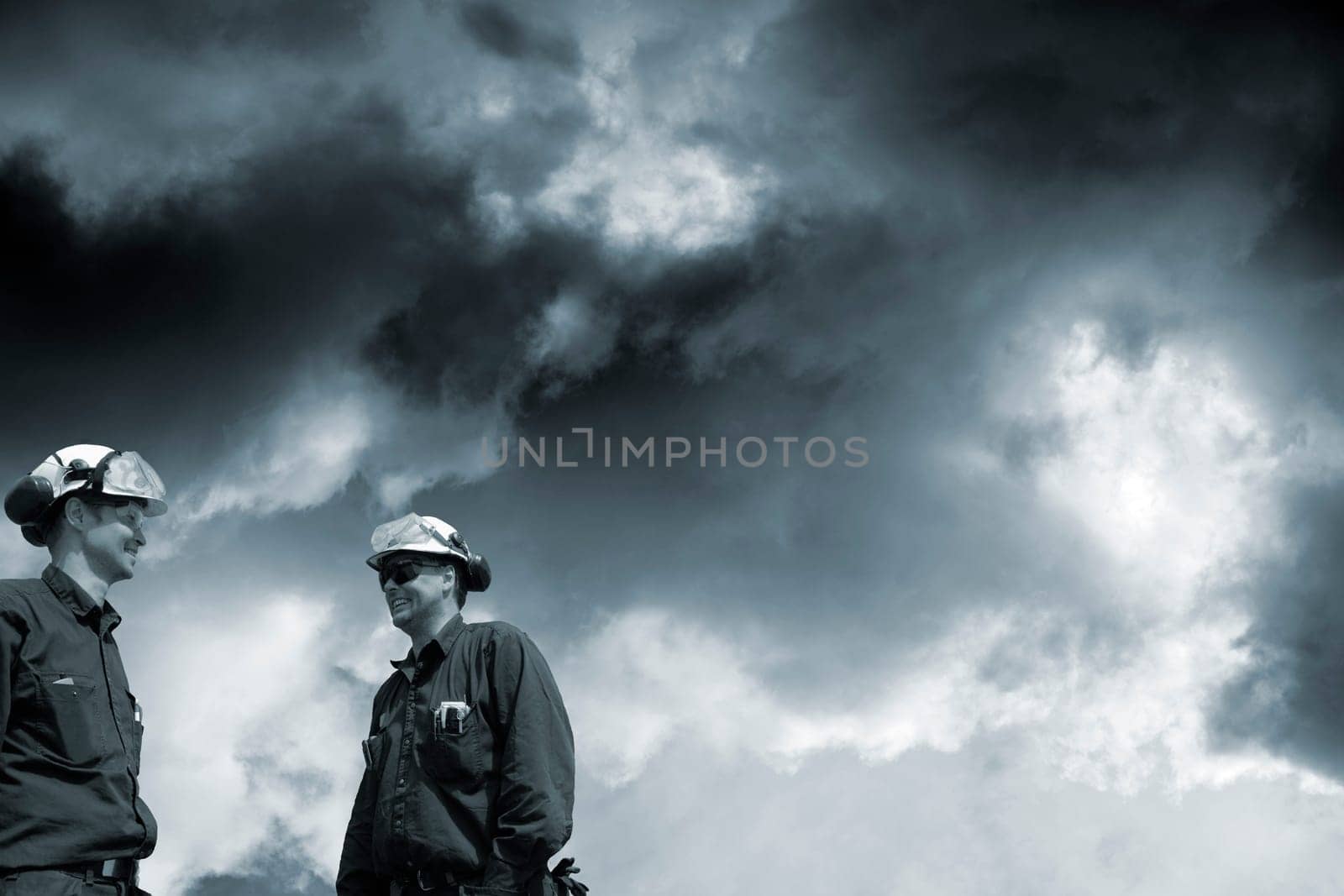 two engineers, workers, standing under a dark toxic cloud-scape, conceptual image