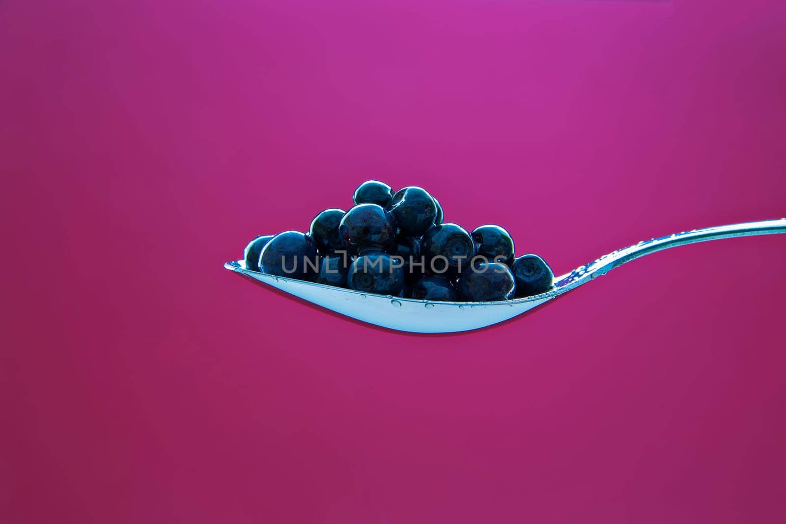 Fresh blueberry on metal chromed spoon on background