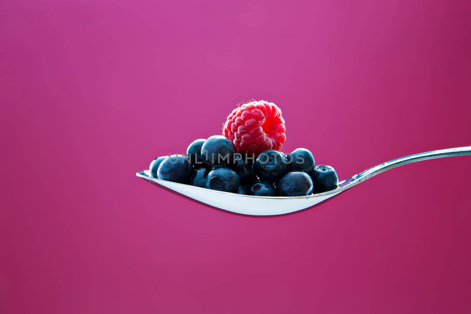 Fresh blueberry and raspberry on metal chromed spoon