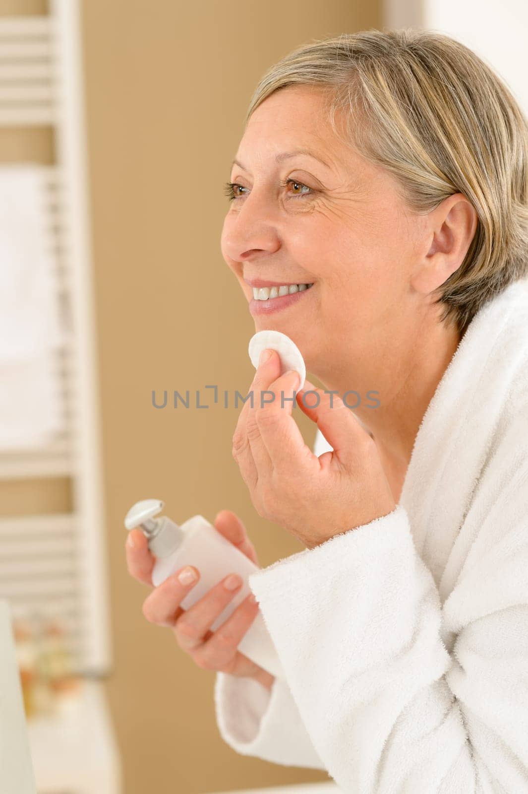 Senior woman in bathroom clean face make-up removal smiling