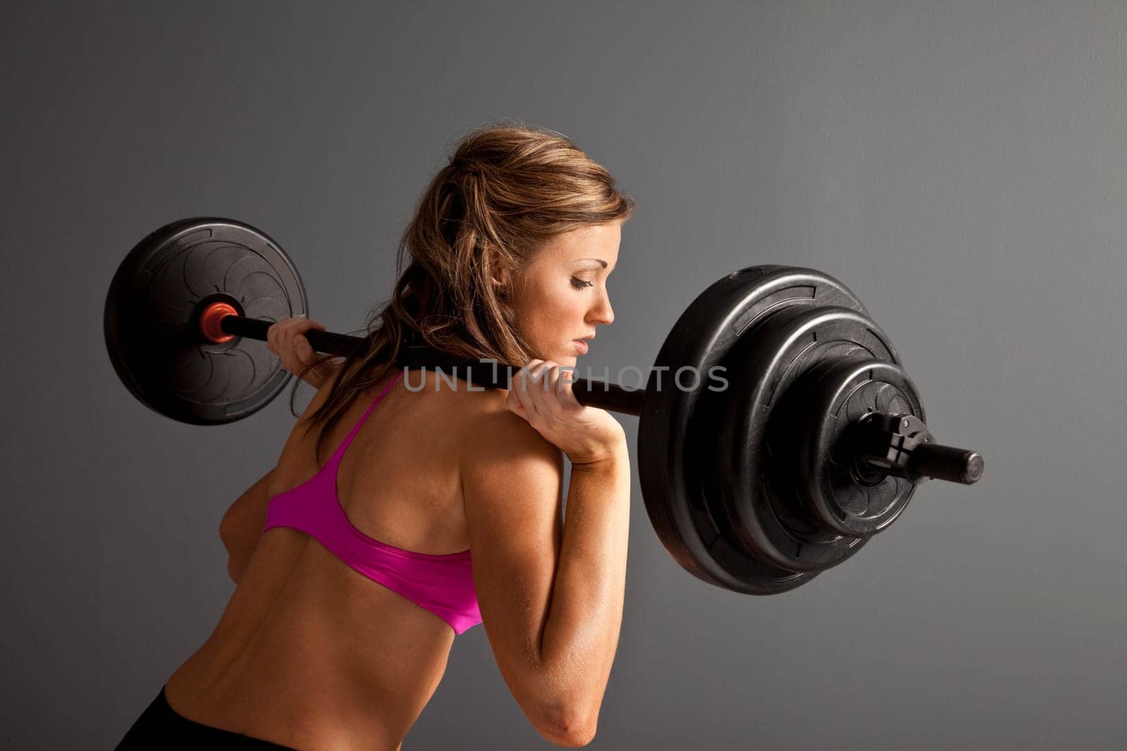 Attractive young woman with barbells on shoulder