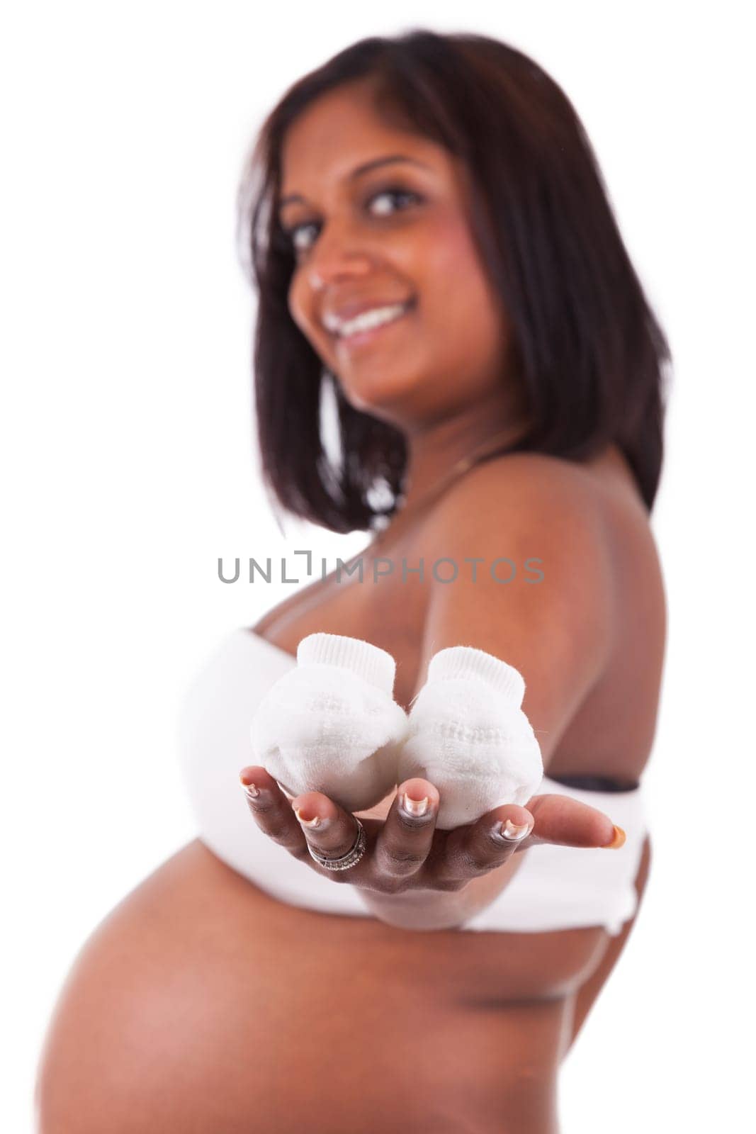 Young pregnant indian woman holding baby shoes, isolated on white background