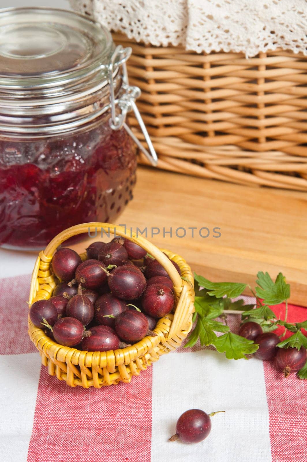 Basket with berries of a red gooseberry and jam