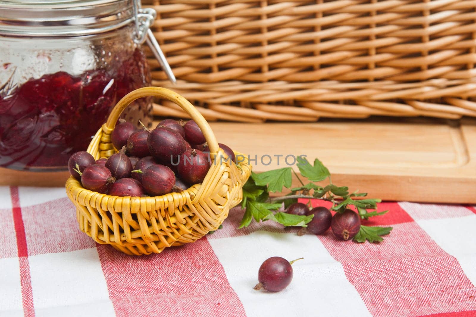 Basket with berries of a red gooseberry and jam
