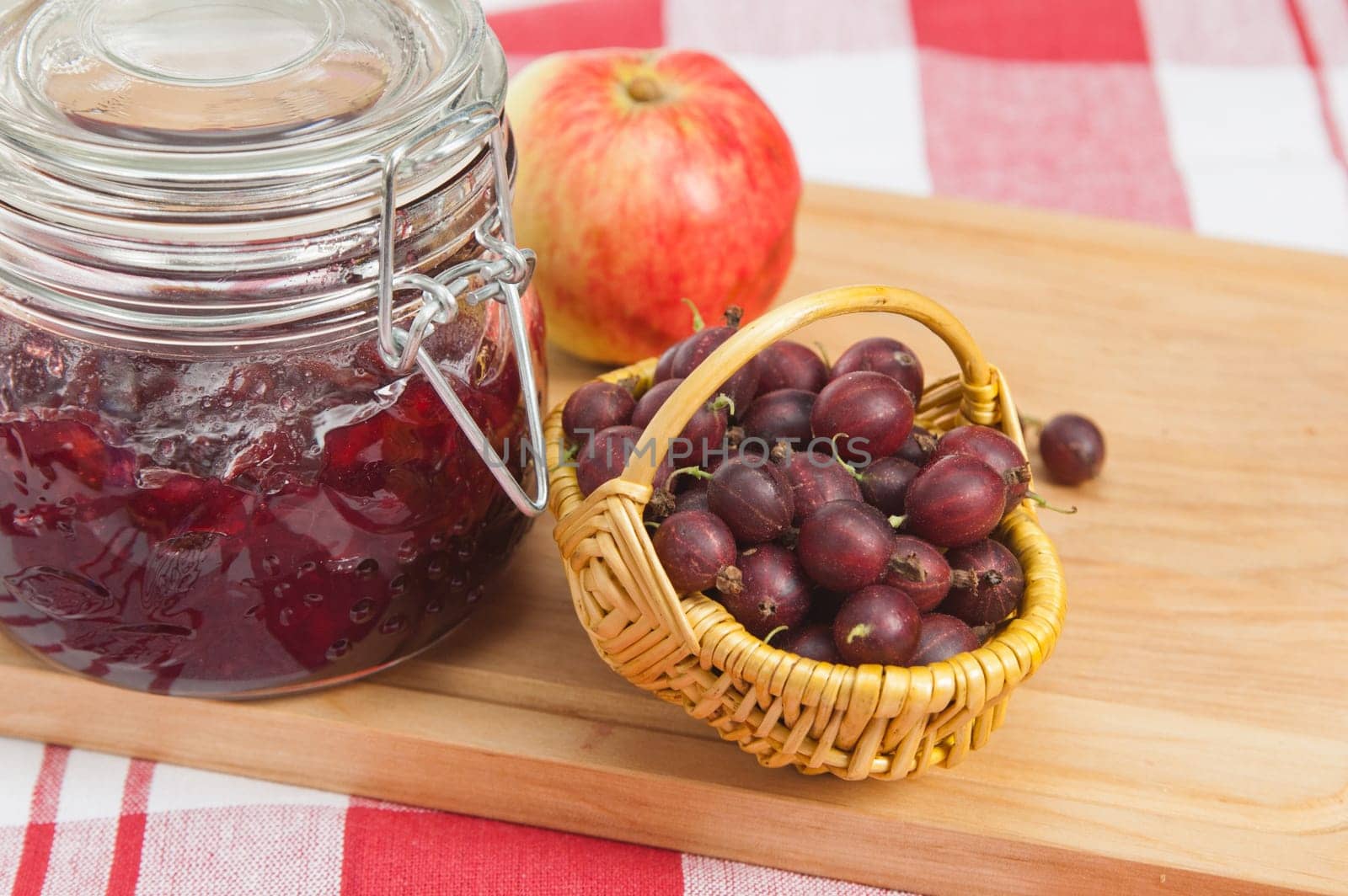 Basket with berries of a red gooseberry and jam